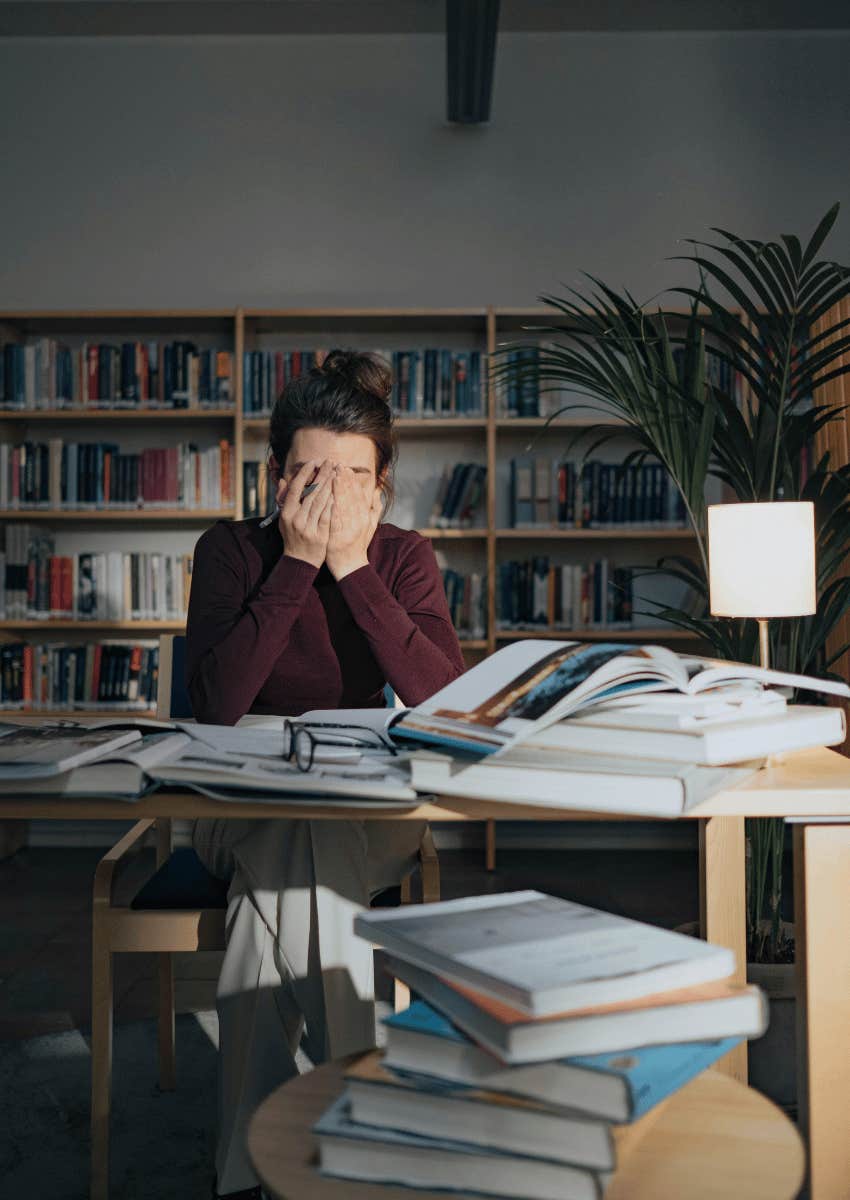 woman in a library covering her face