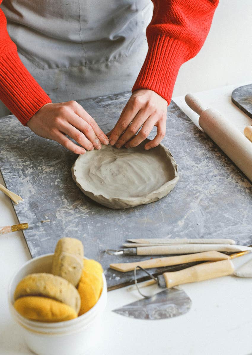 woman molding a small clay plate