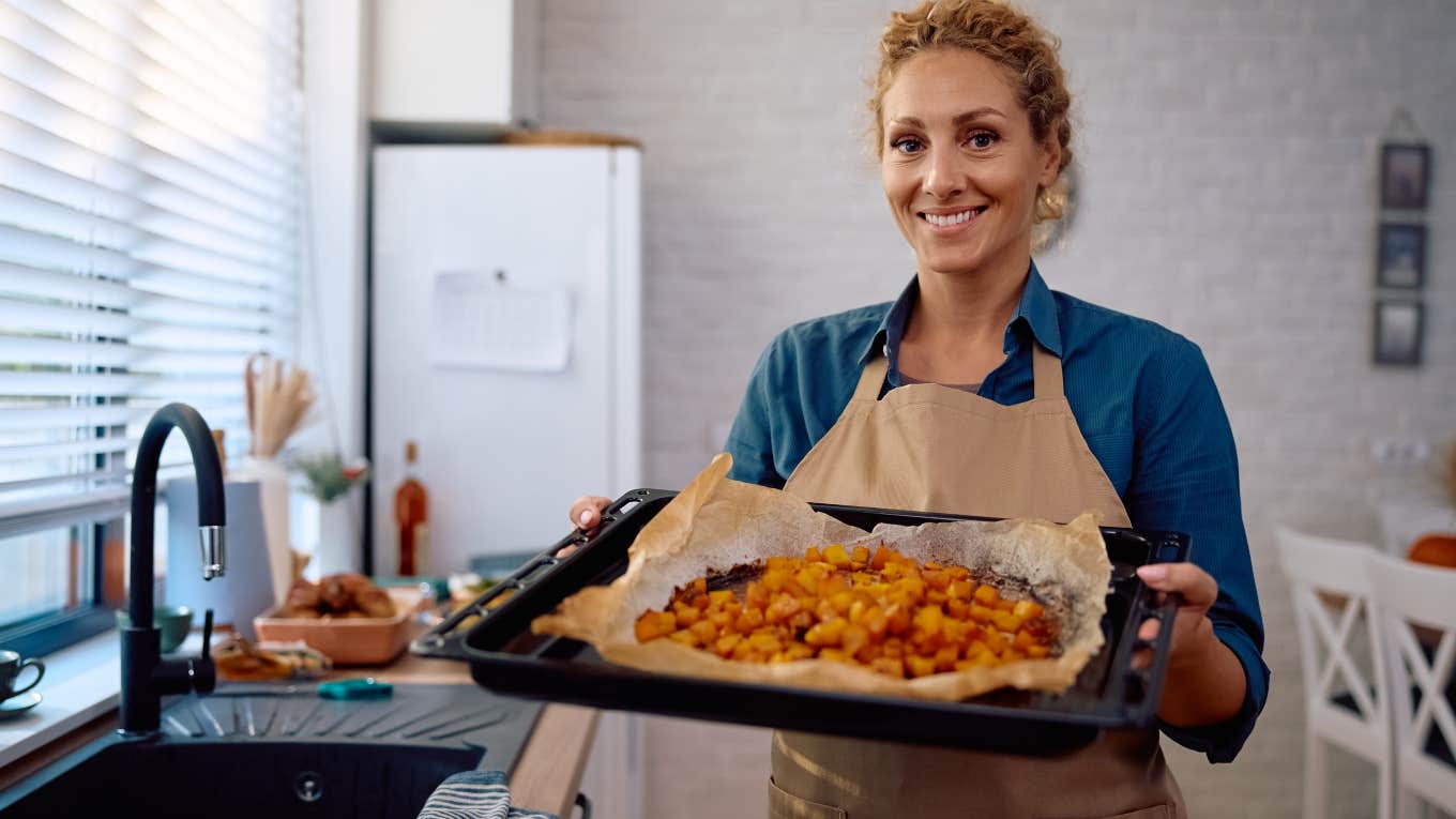 woman cooking Thanksgiving dinner in the kitchen holding up tray of food