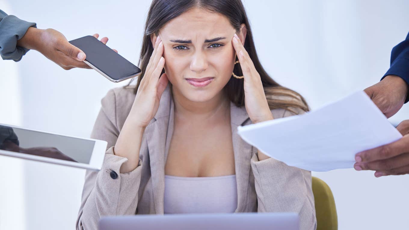 stressed woman surrounded by laptop, phone and paperwork