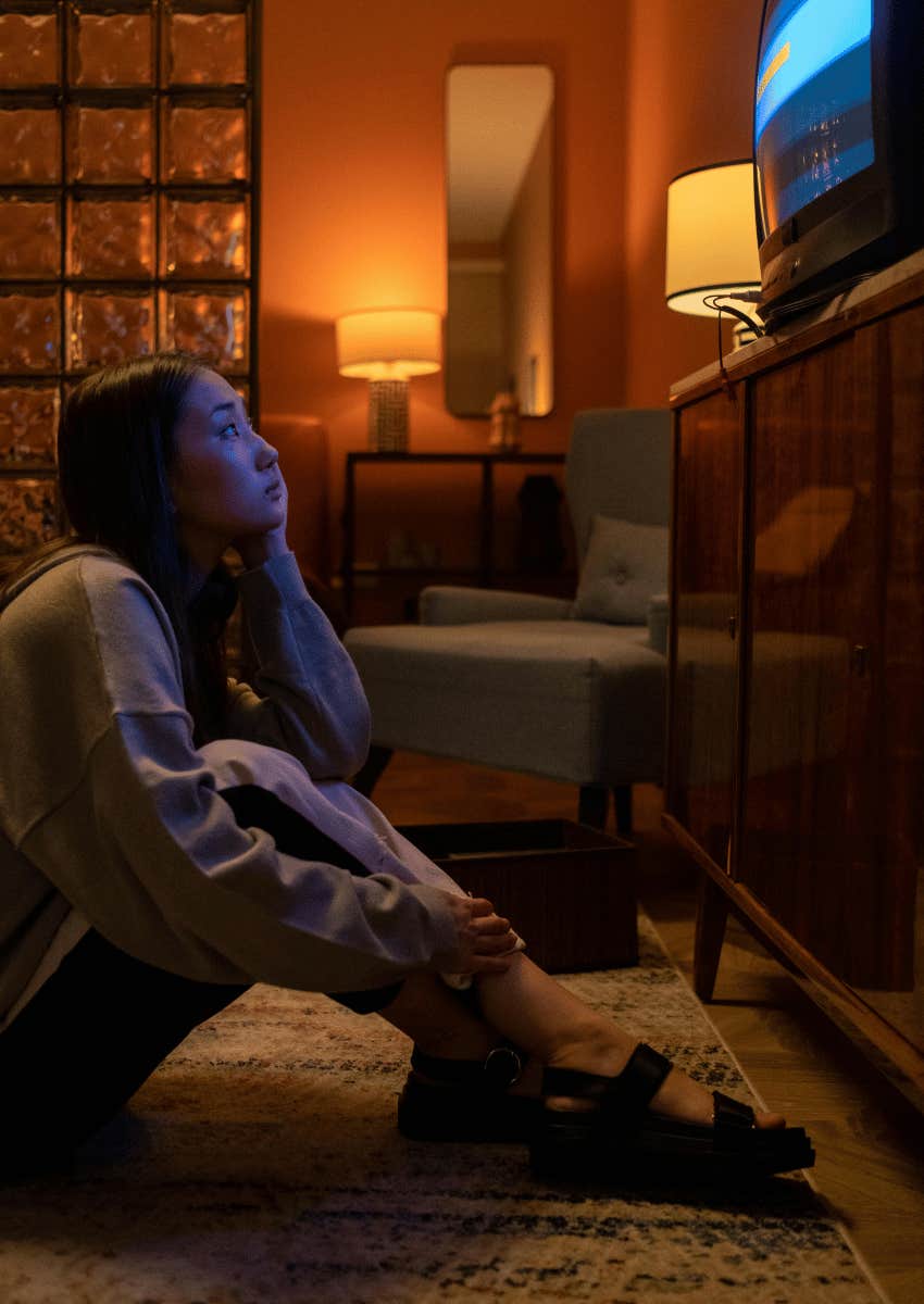 woman sitting on the floor looking at tv