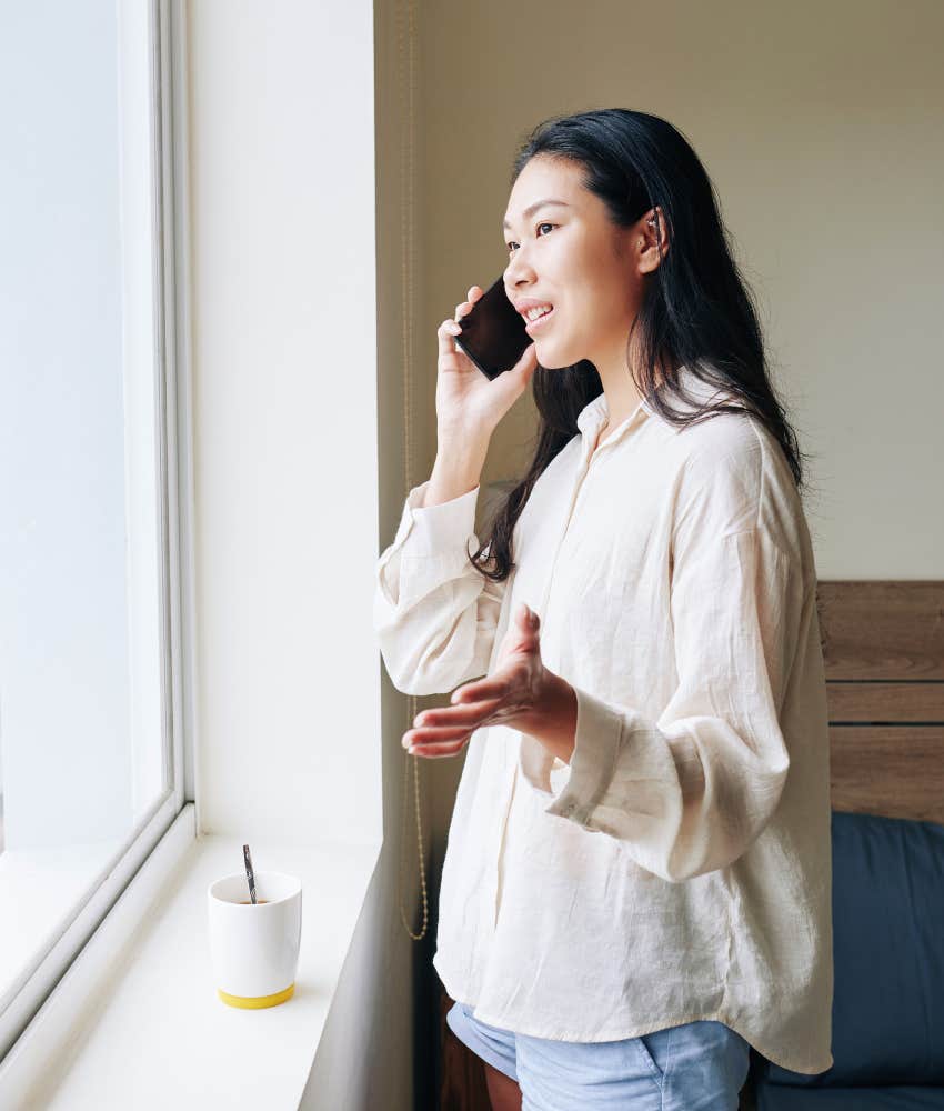 woman talking on the phone while looking out the window