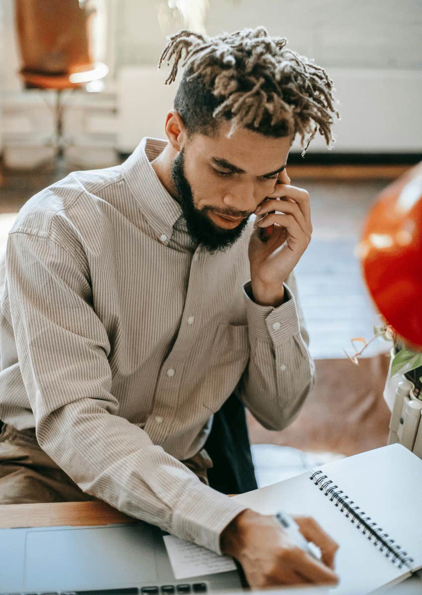 young man taking notes while on the phone