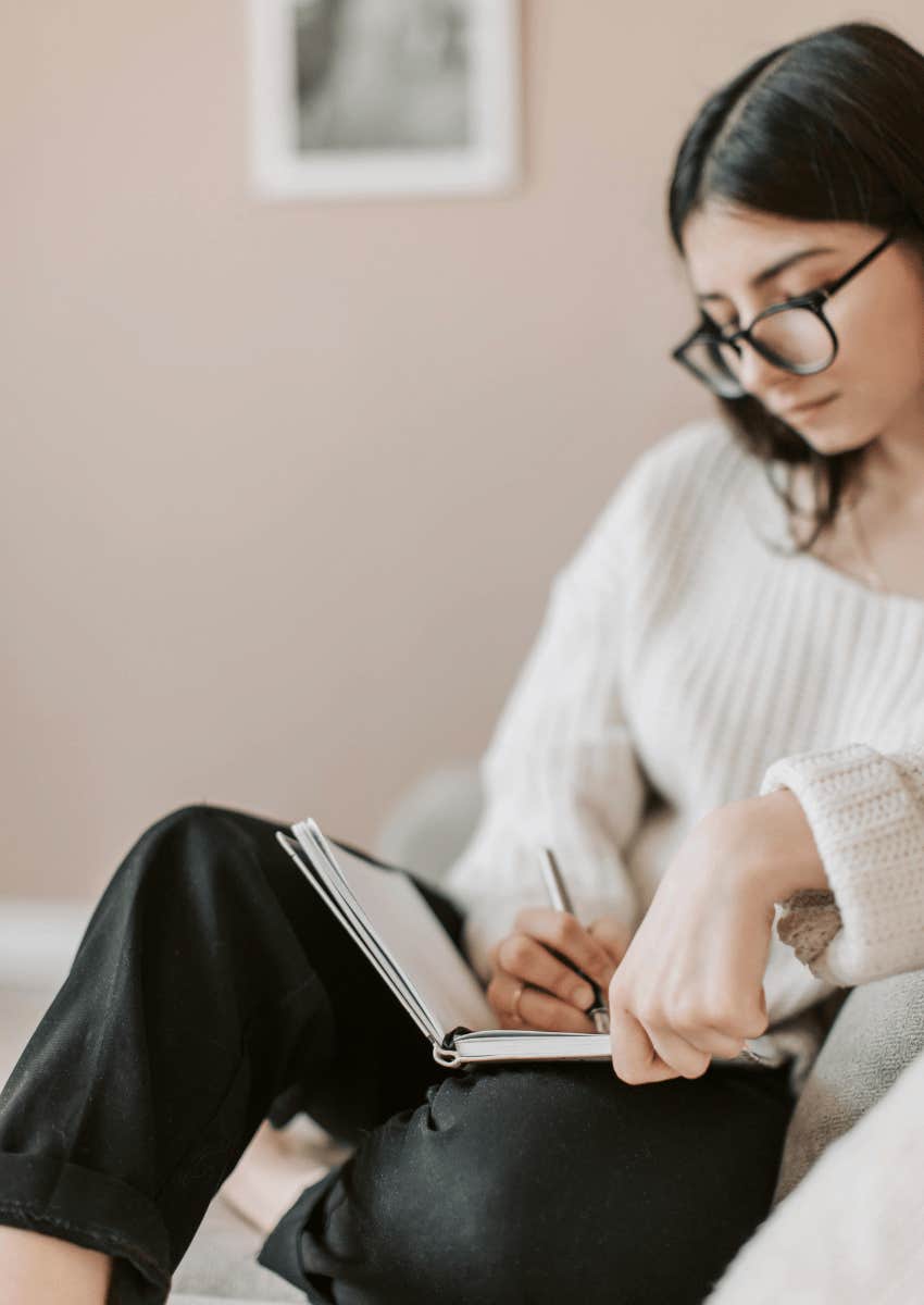 young woman wearing glasses journaling