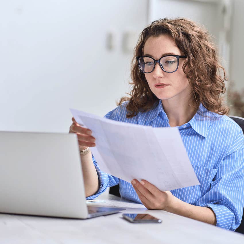 young woman looking at several sheets of paper