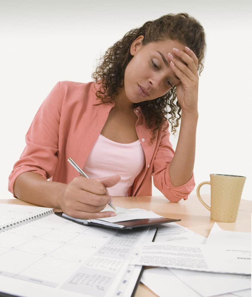 Young woman paying bills with her hand on her head