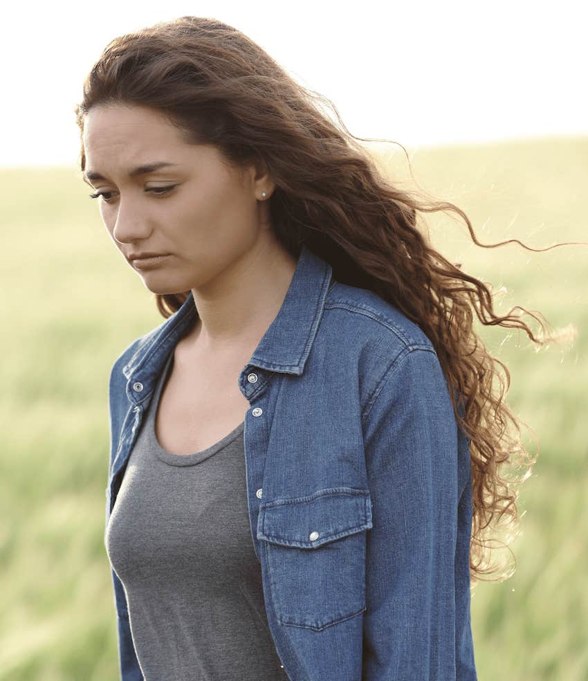 Introspective Woman alone in a field realizes she might be in an abusive relationship