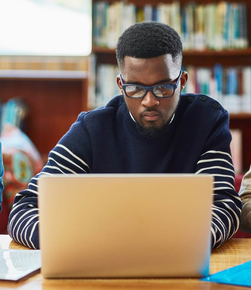 Academic man works on laptop in library