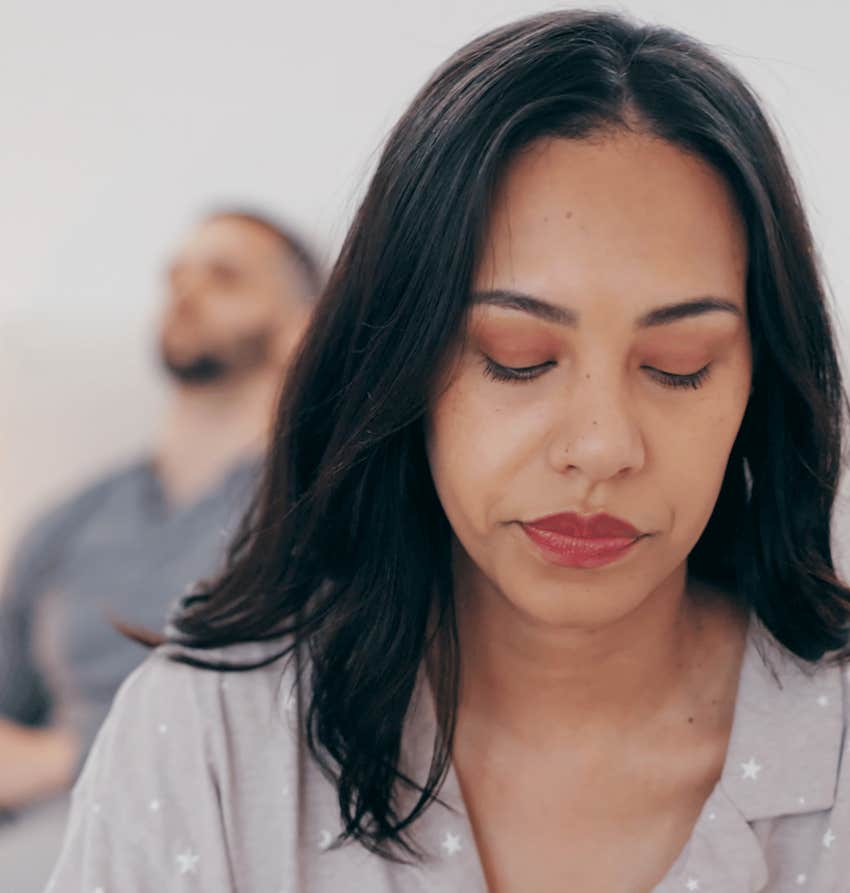 Sad woman accepts infidelity is wrong as husband sits in background