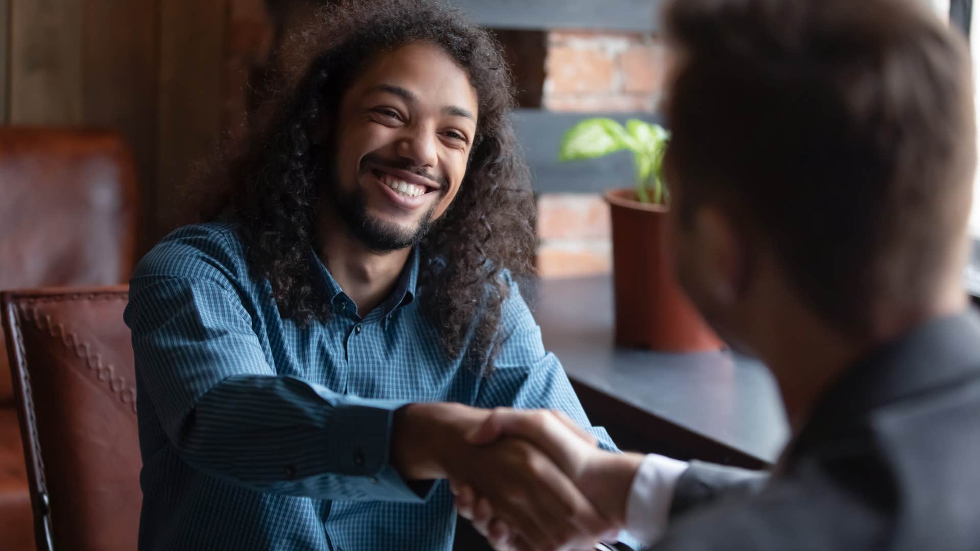 Man smiling and shaking a friend's hand