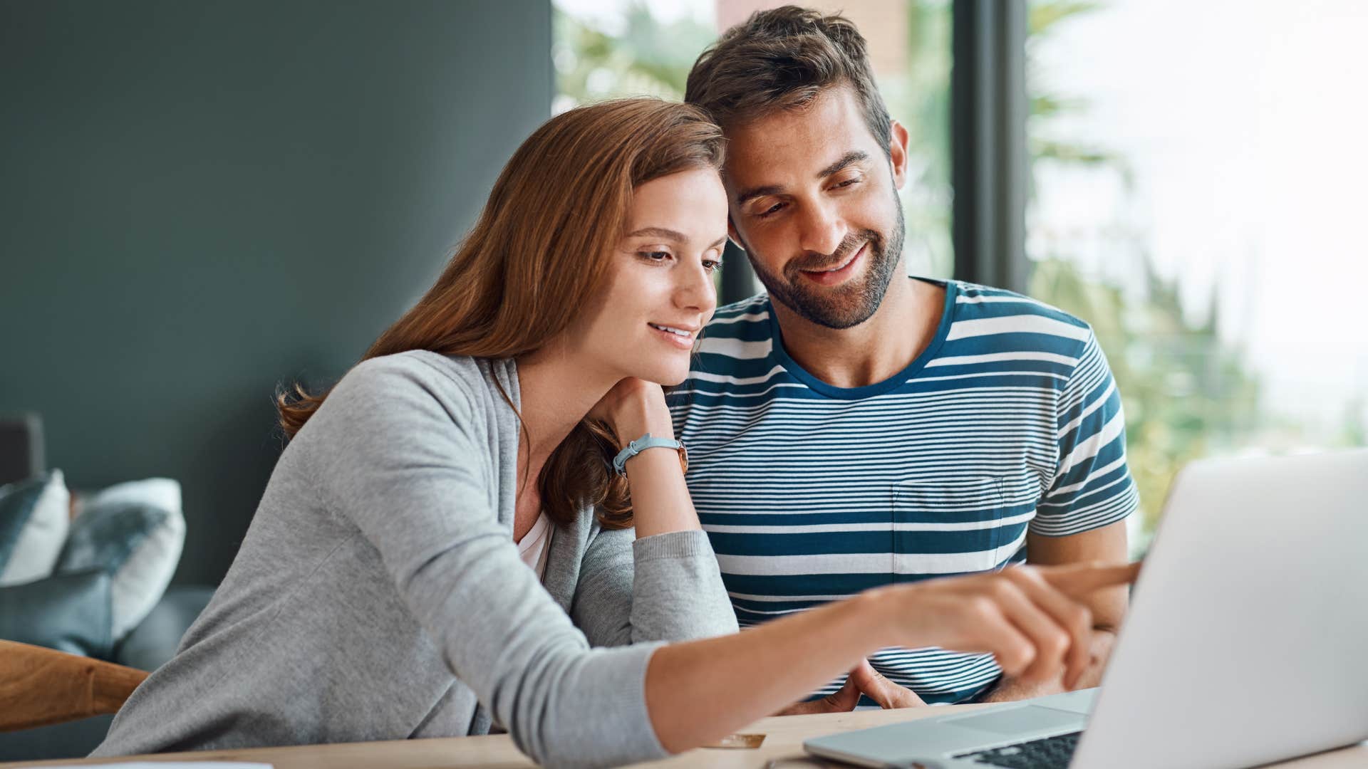 Couple smiling and looking at a laptop together