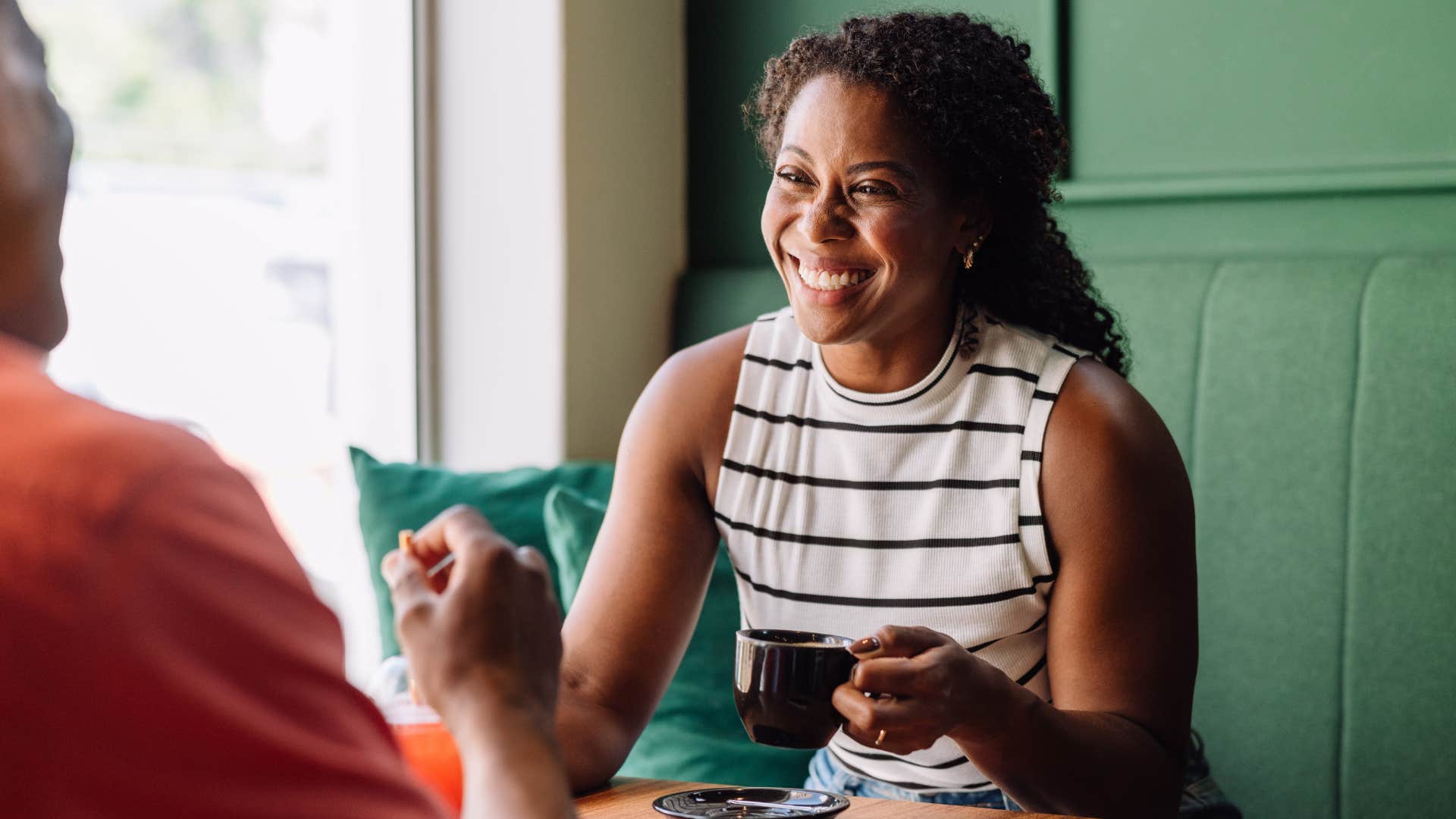 Woman smiling and drinking coffee with a man