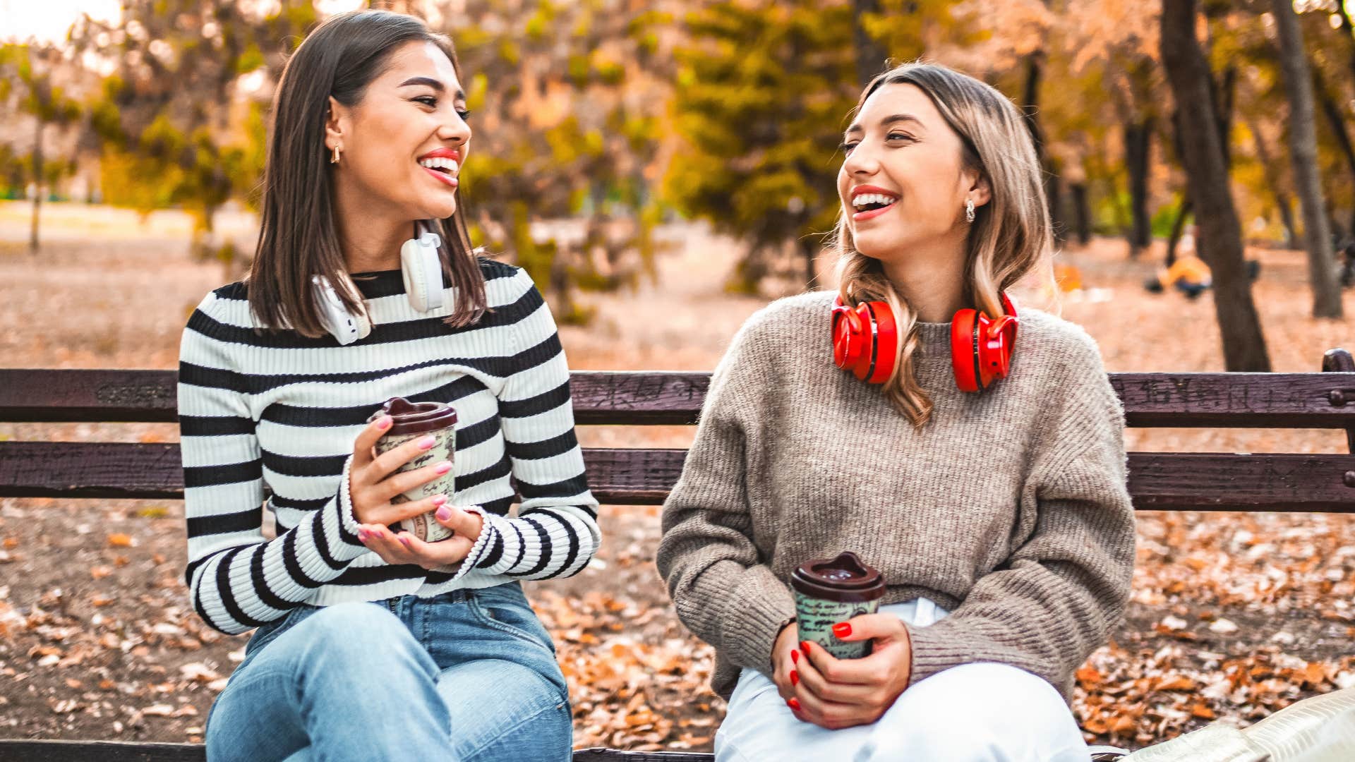 Two friends smiling and sitting on a bench together