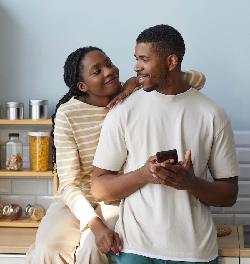 Adorable couple in kitchen look at each other with deep love