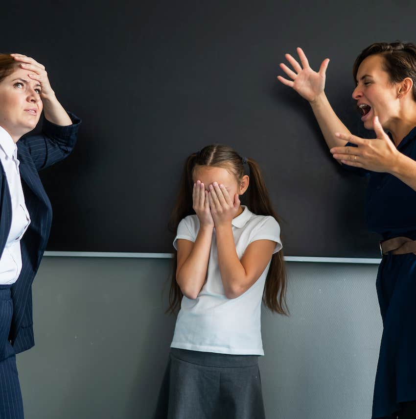 Angry mother yells at teacher while embarrassed daughter covers her face