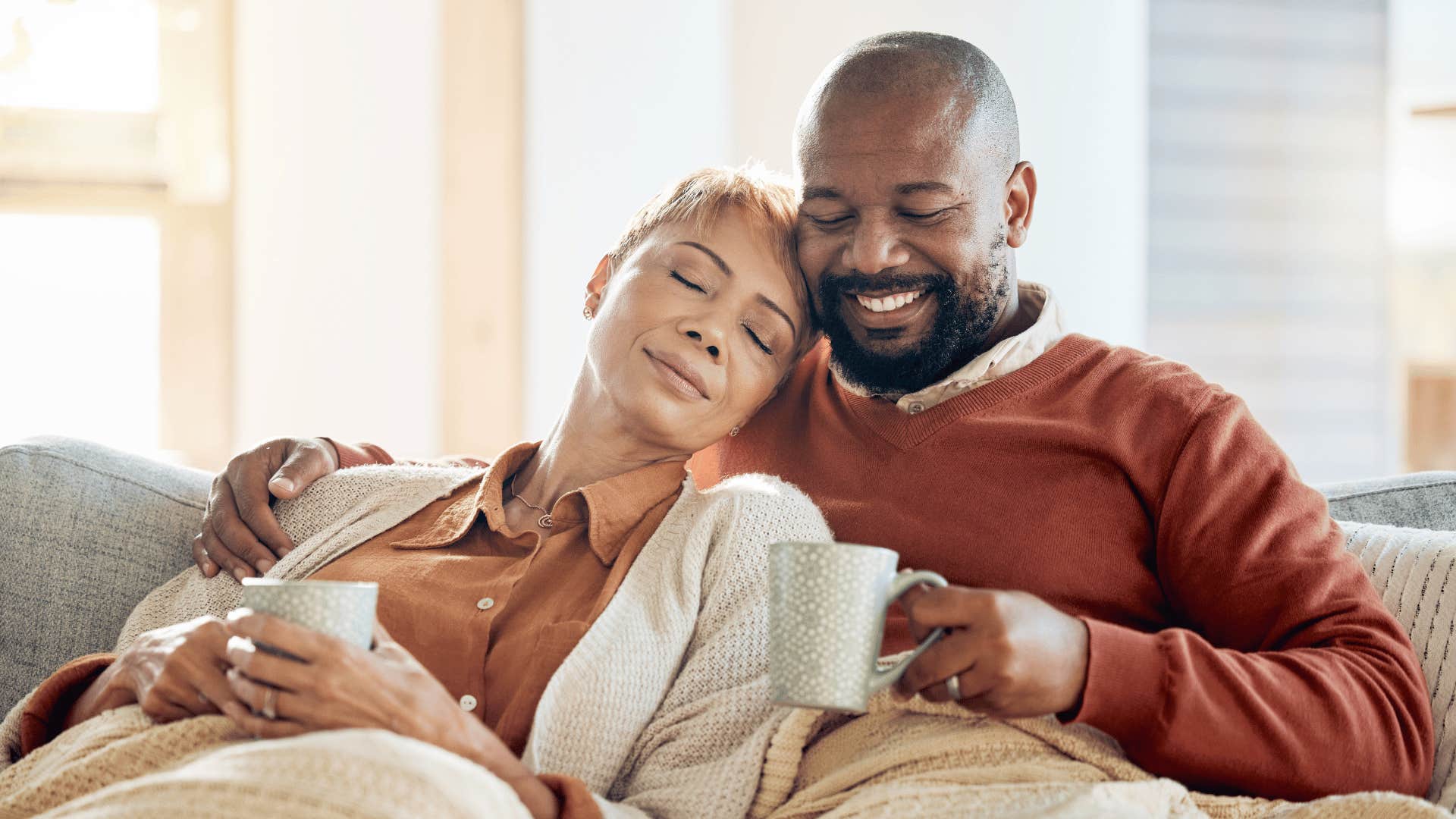 Comfortable couple cuddles on coach at home