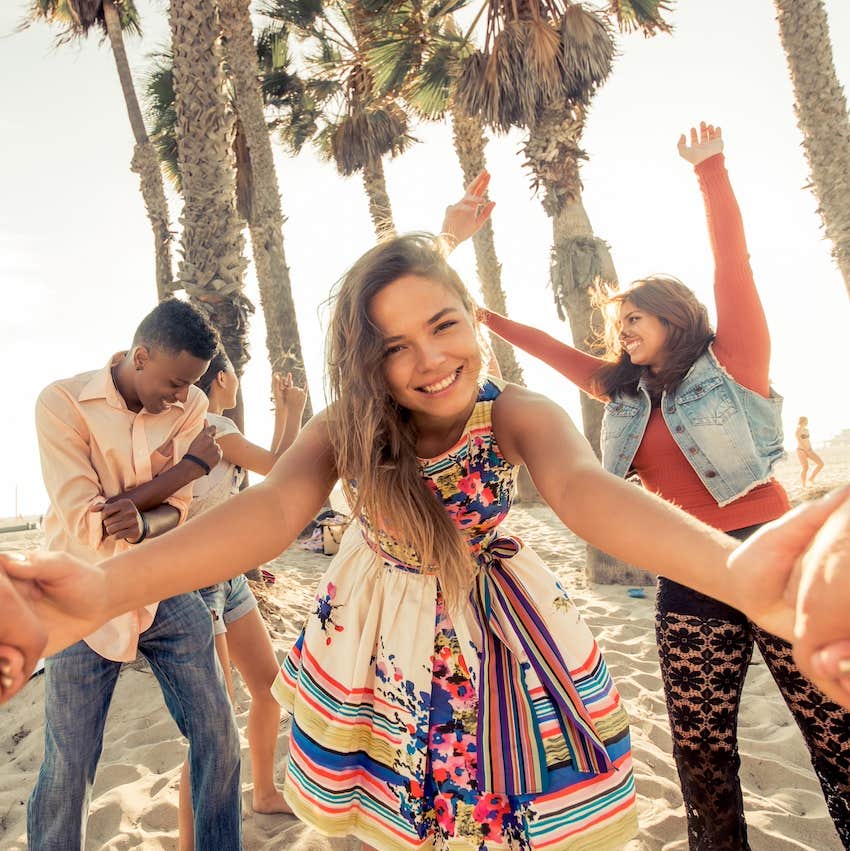 Friends dance while a woman reaches toward the camera