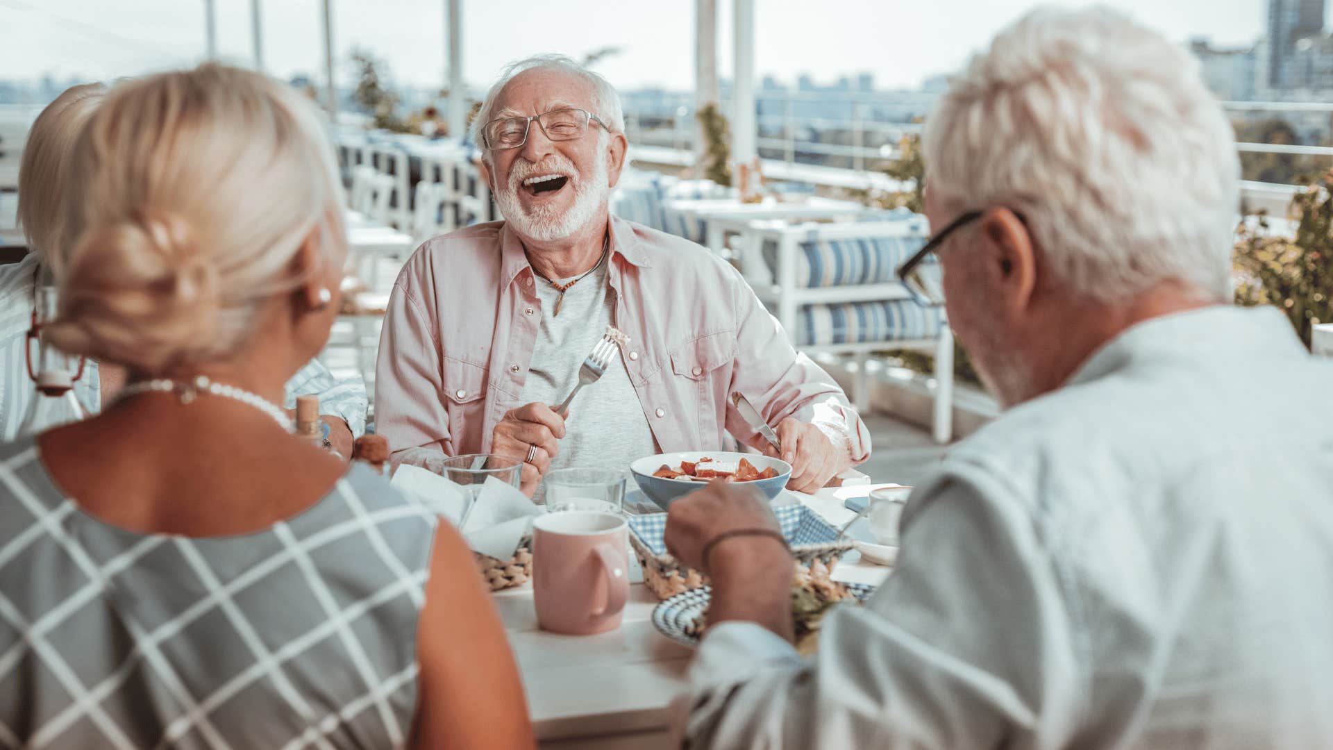 Three older people have a meal together at a table