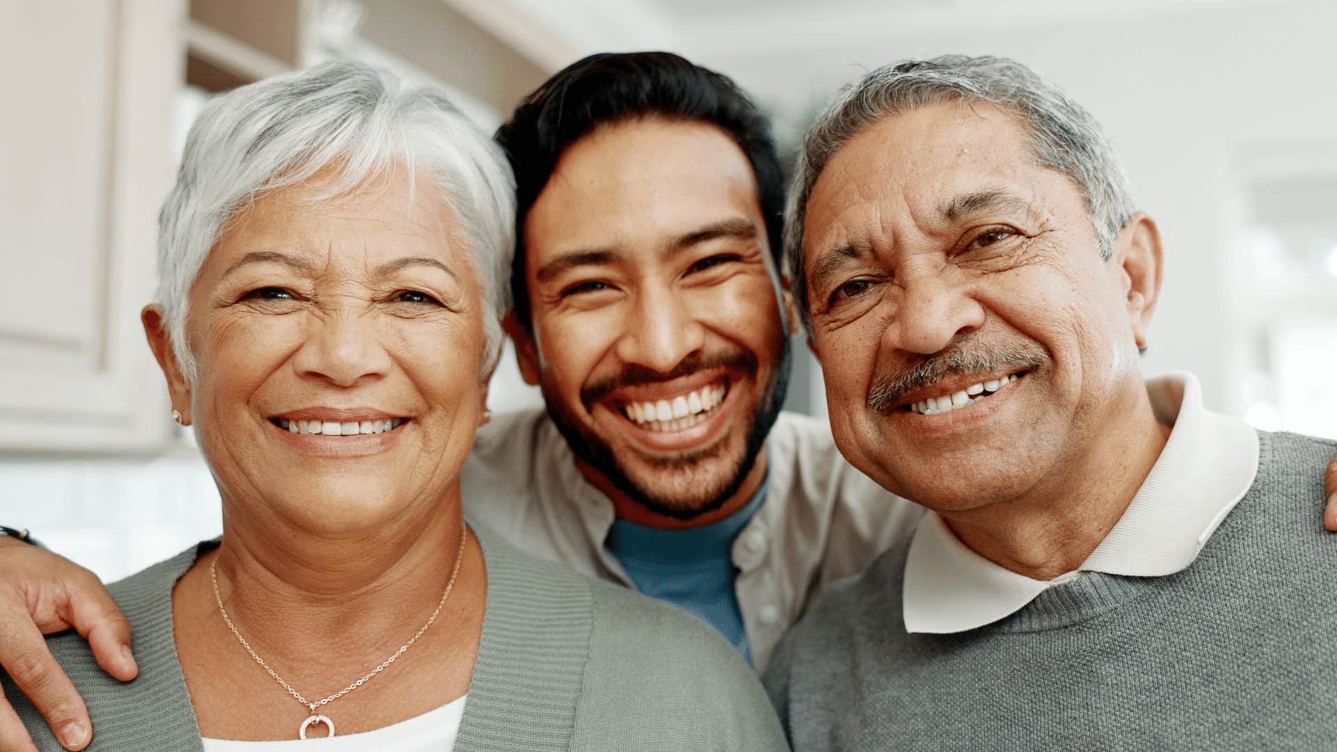 Youner man smiles and stand face-to-face between older man and woman