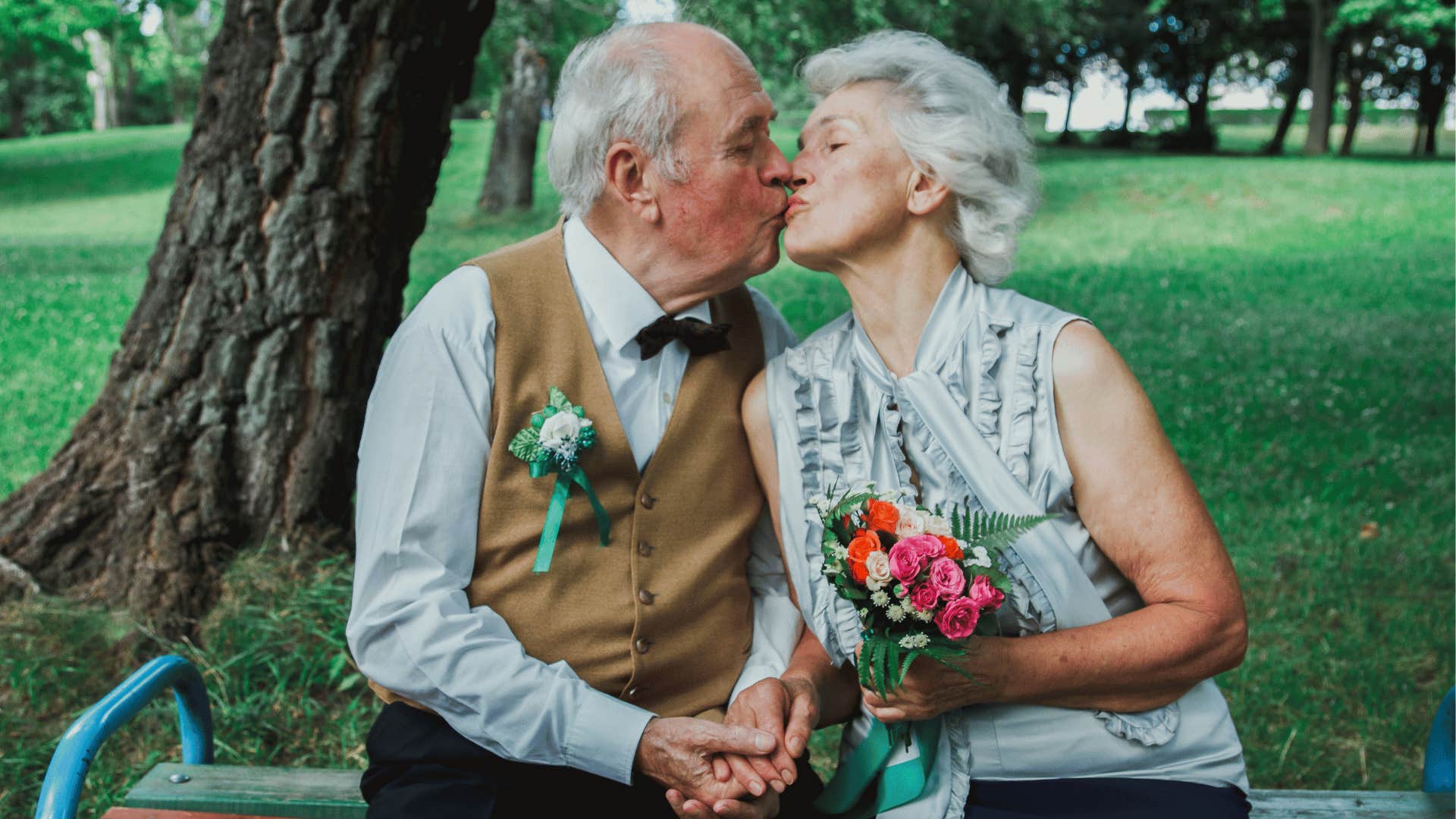 Older formal couple share a kiss in a park