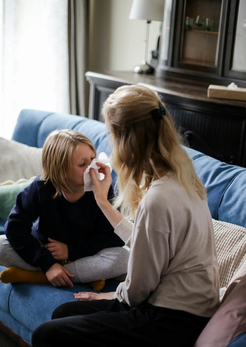 mom holding tissue for son to blow his nose