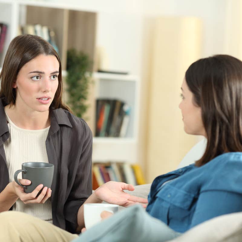 Serious friends talking sitting on a couch in the living room at home