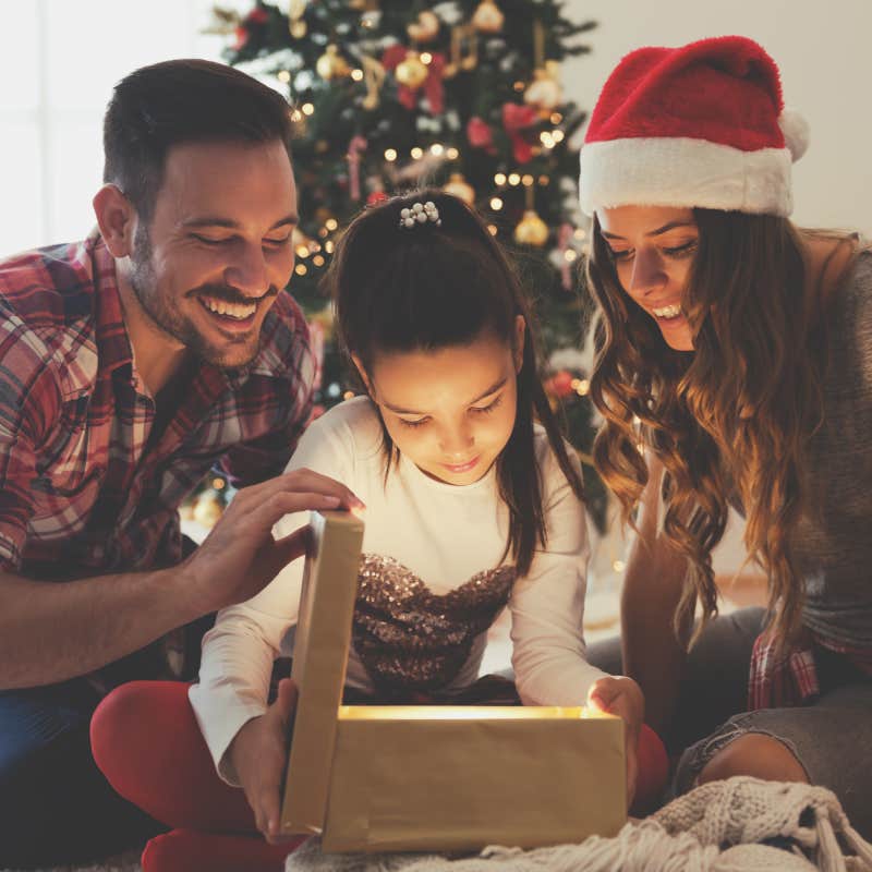 Young couple and kid opening a Christmas present on a Christmas morning