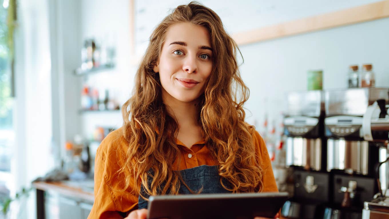 Beautiful woman owner stands behind the counter of a coffee shop.