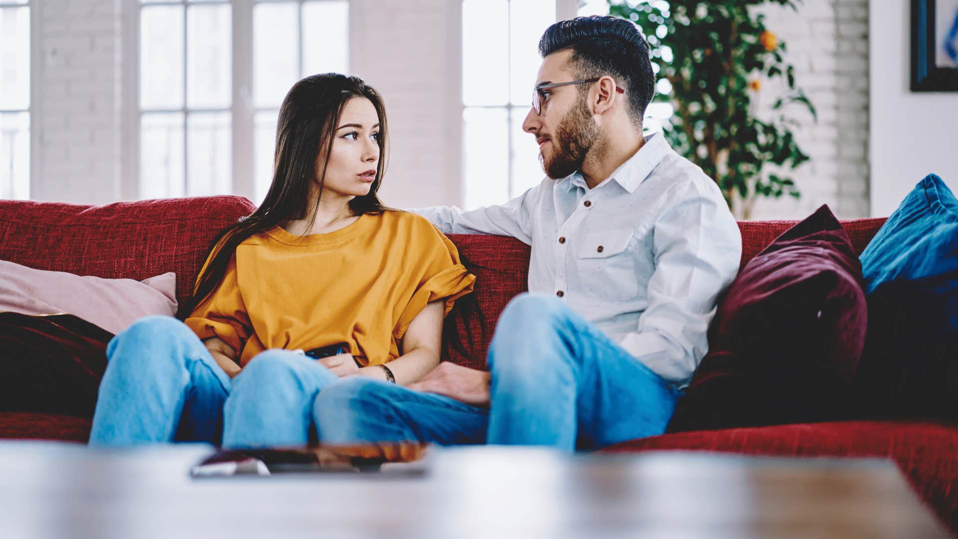 woman and man talking on the couch while woman looks upset