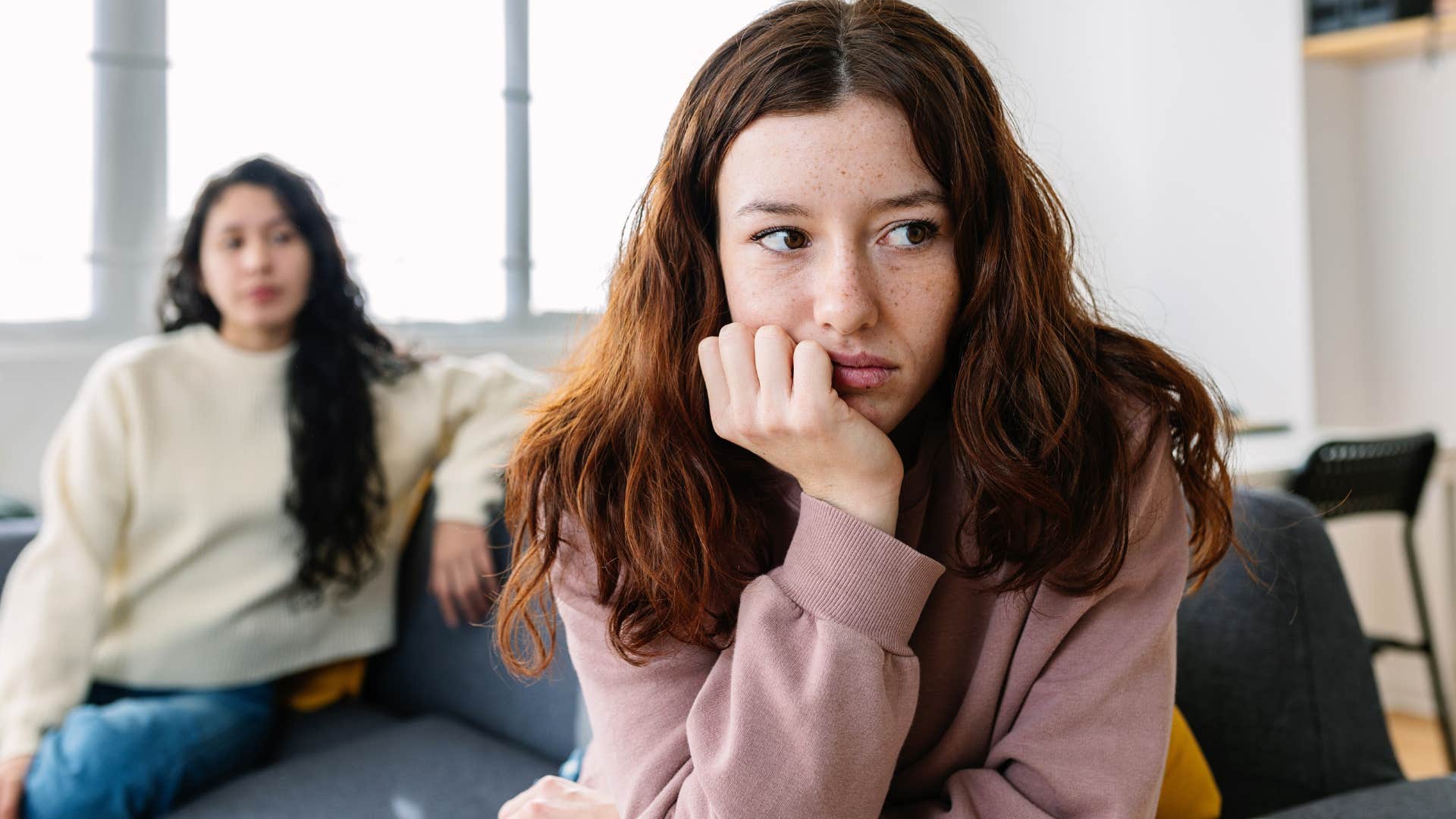 Woman turned away from her upset friend on a coach.