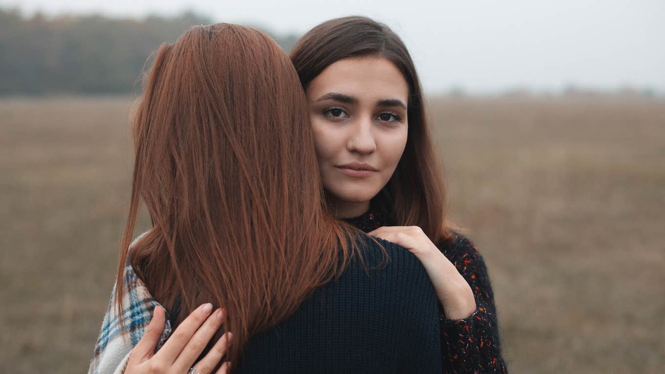 two women hugging with serious face