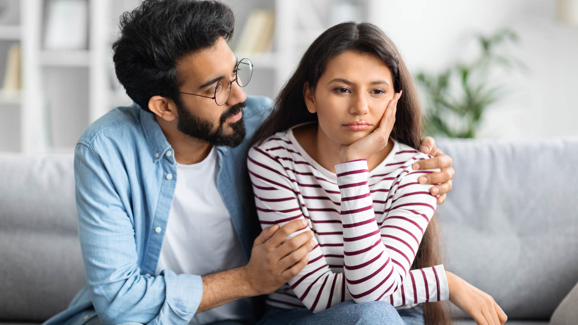 Man comforting his upset wife on the couch