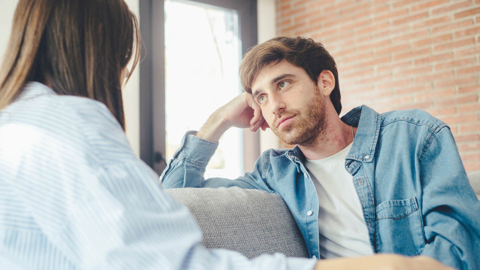 Upset man staring at his partner on the couch