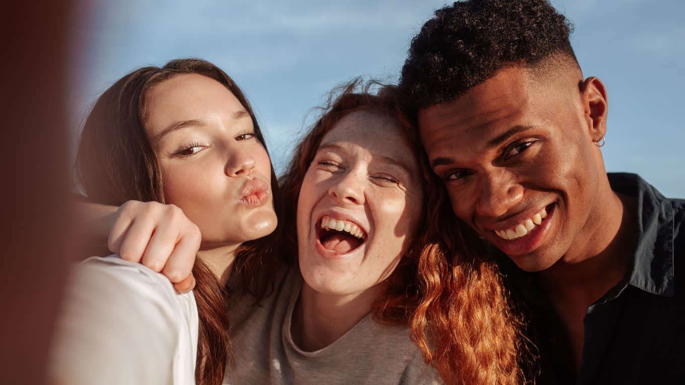 Three multicultural friends posing for the camera while hanging out together on a sunny day. 