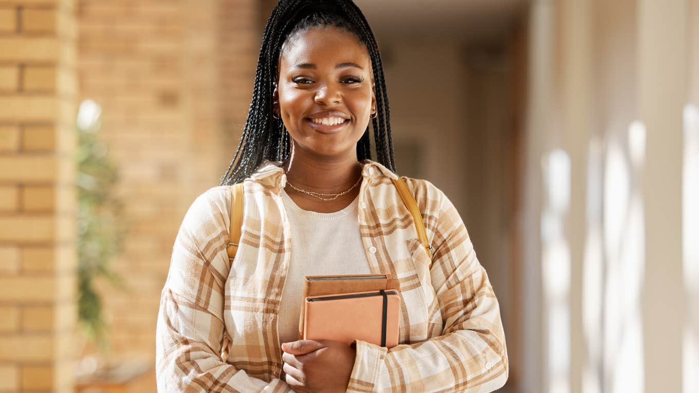 intelligent young woman holding books and smiling