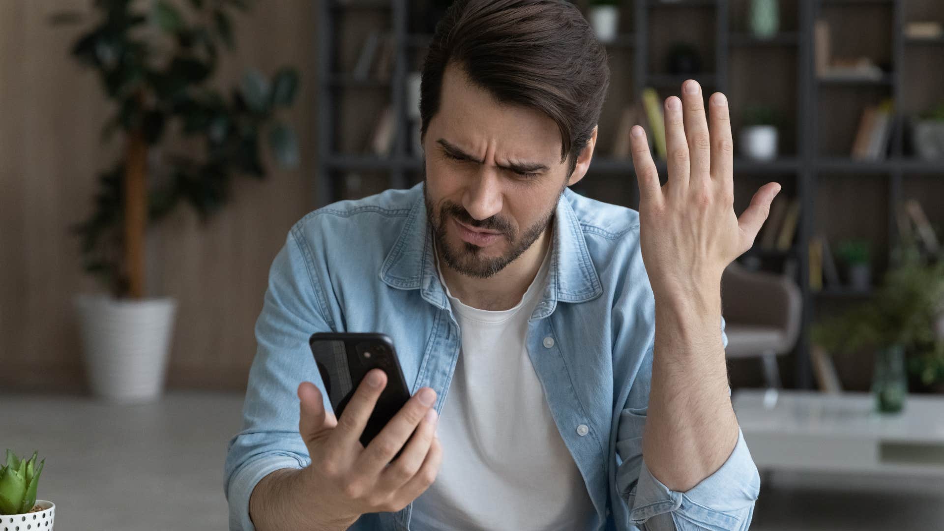 Man looking upset staring at his phone.