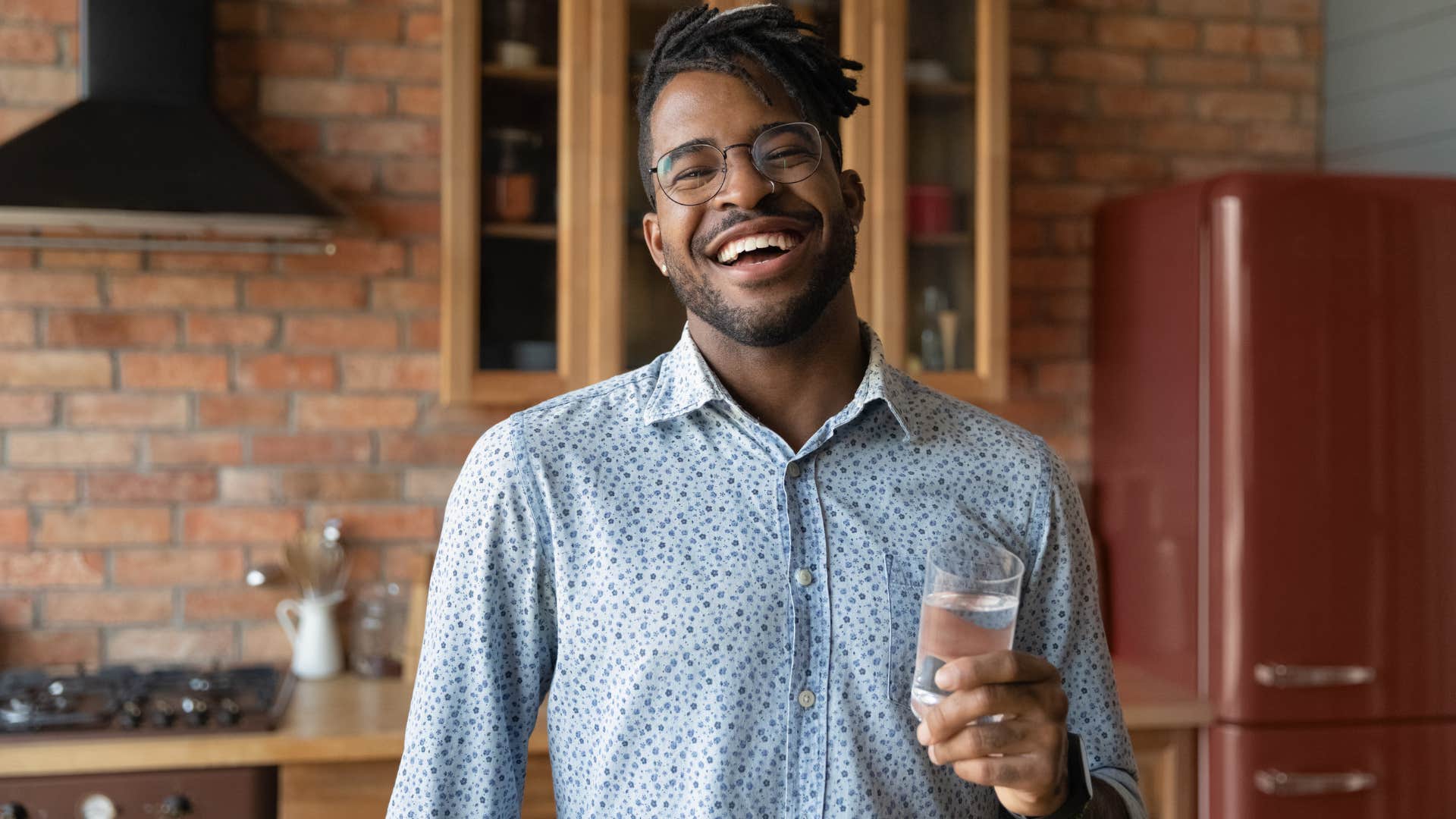 Man smiling and holding a glass of water.