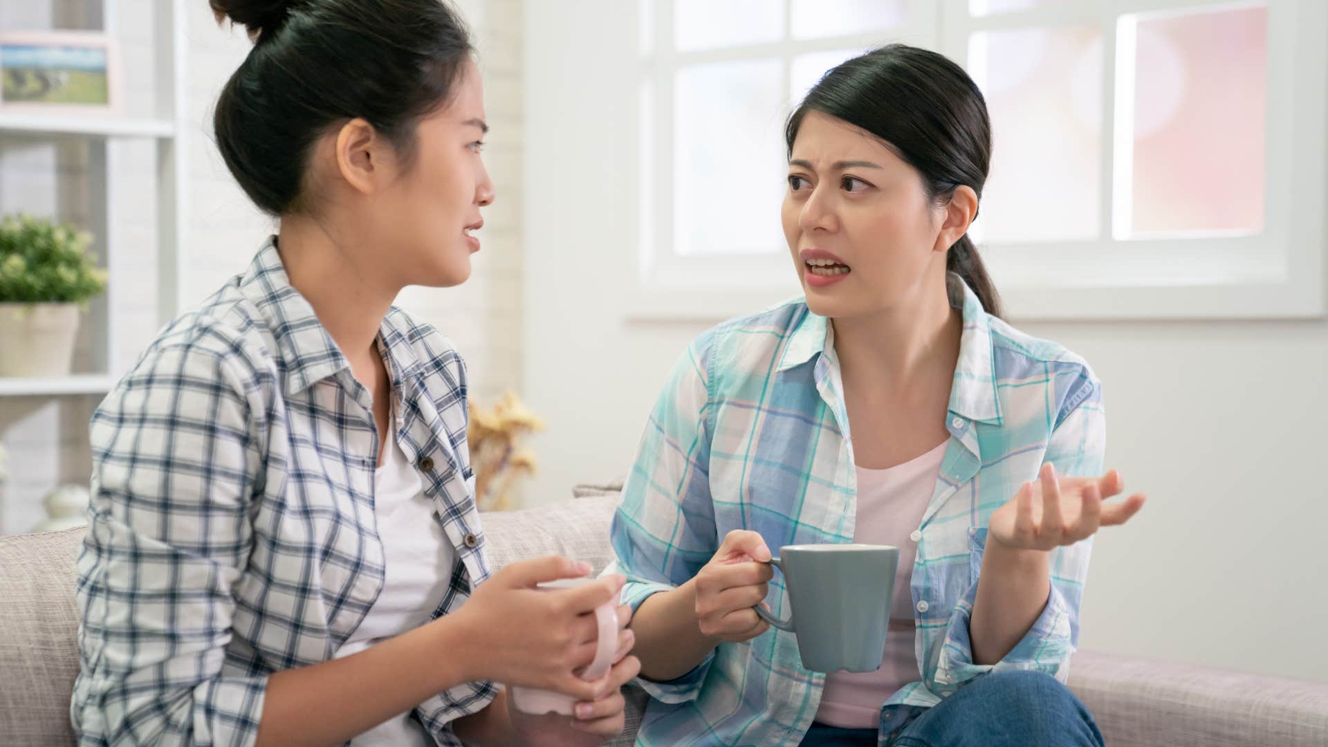 Two women arguing together on the couch.