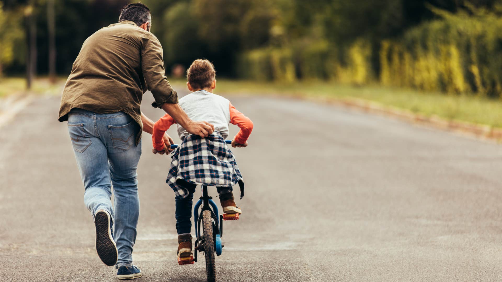 father teaching son to ride a bike