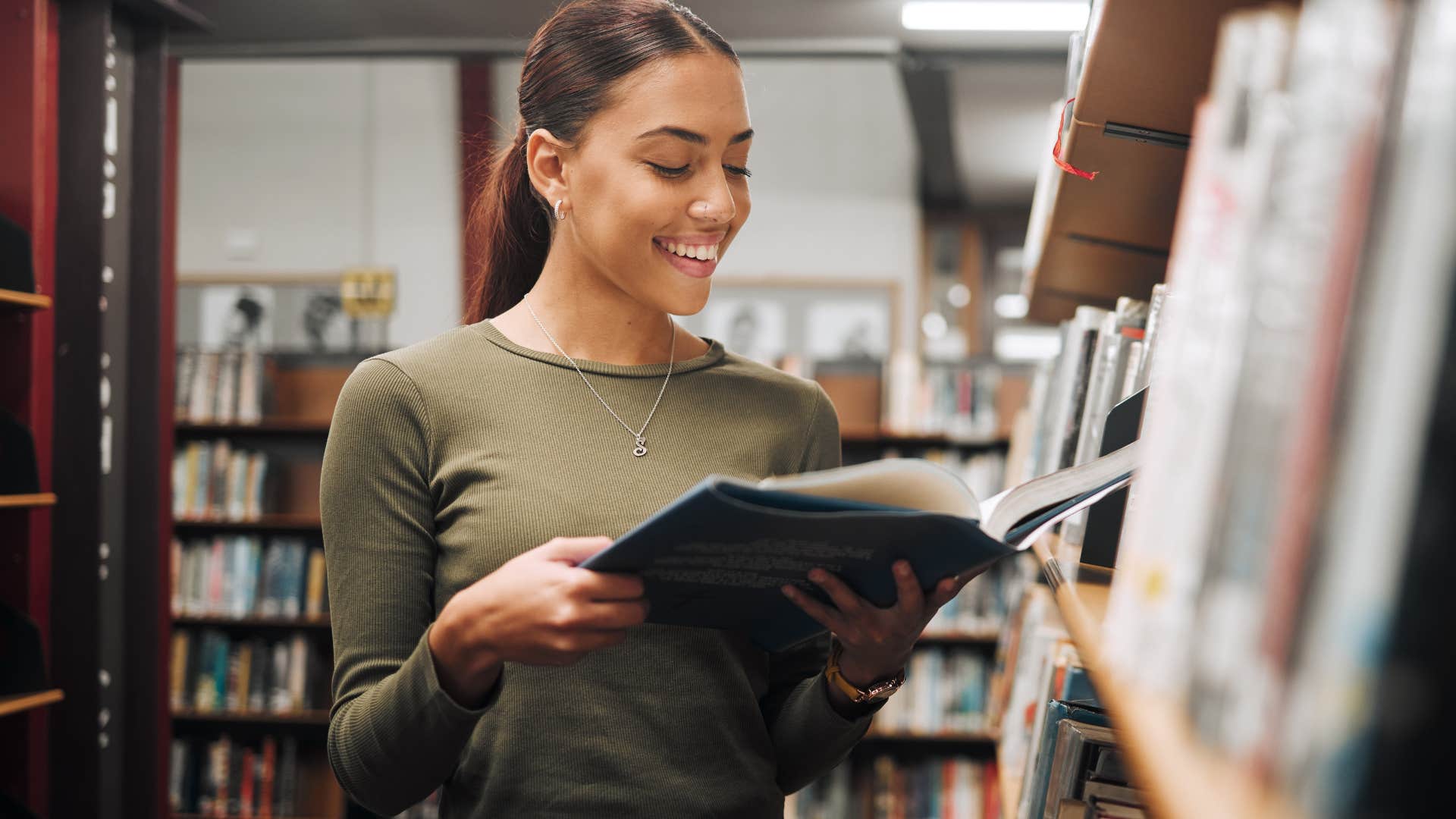 Woman smiling and reading in the library.