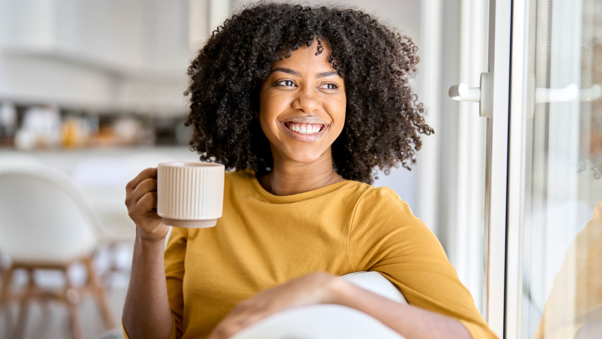 Woman smiling and drinking coffee.