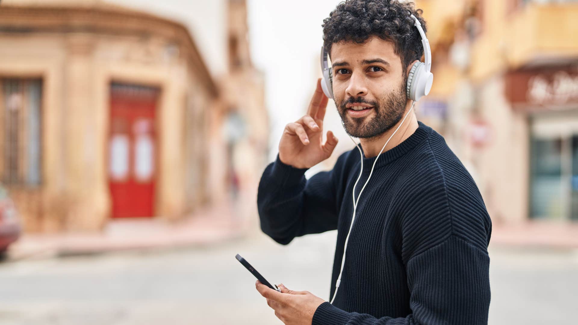 Man smiling and walking on his headphones.