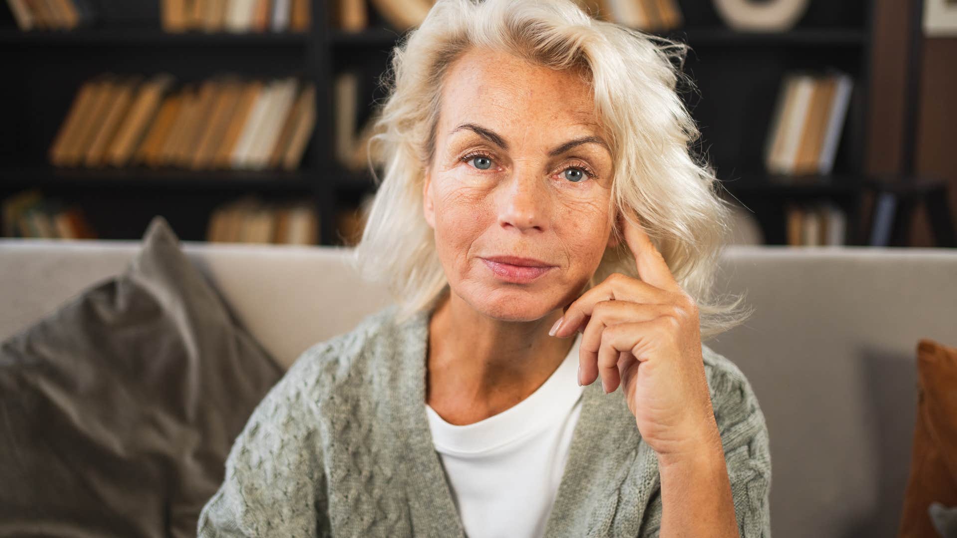 Older woman looking sad sitting on the couch.