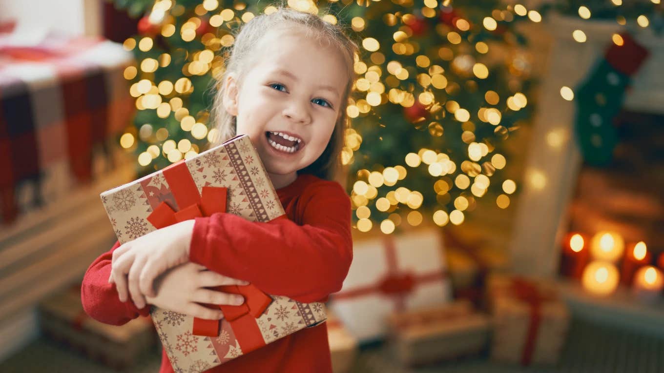 Young girl holding Christmas present from her single mom