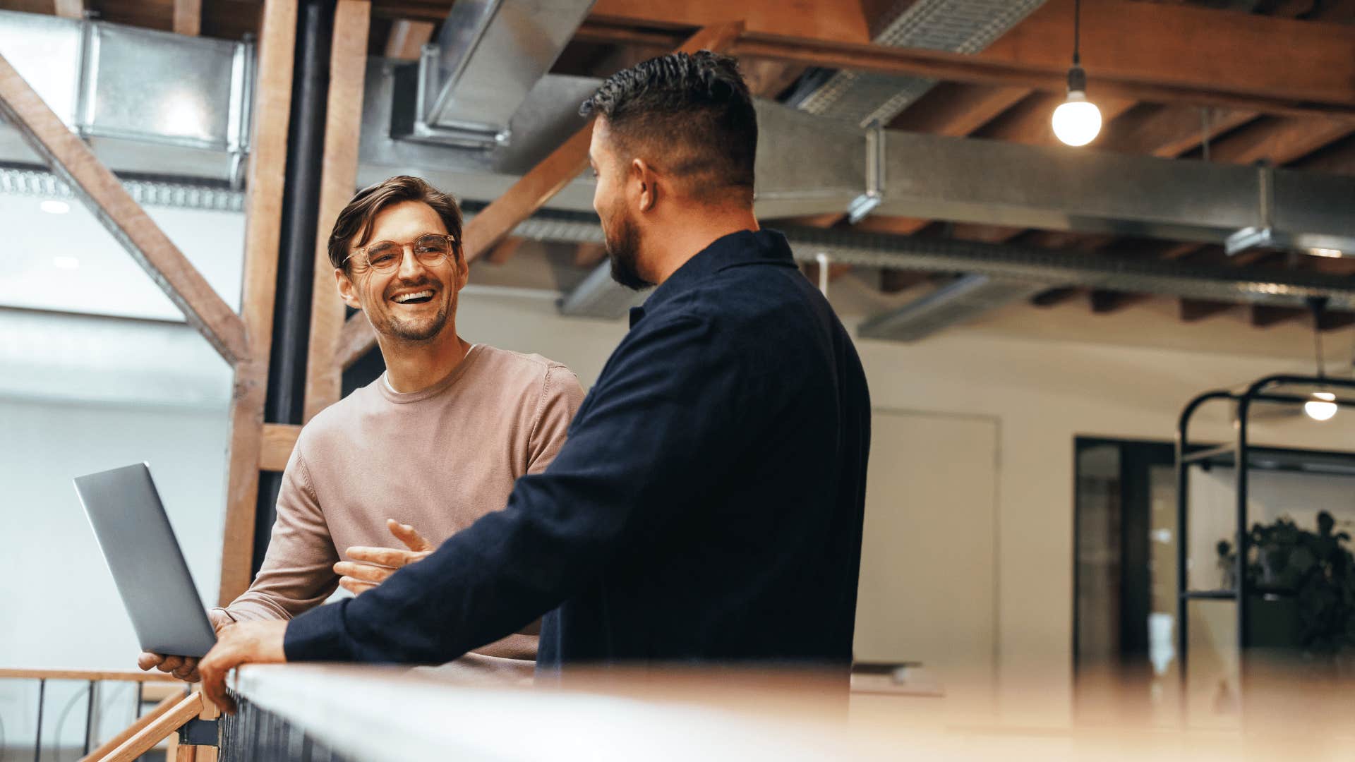 two men talking in front of a laptop