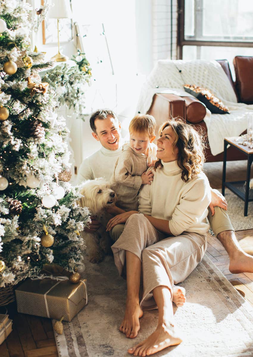 family of three sitting next to a Christmas tree in nice clothes