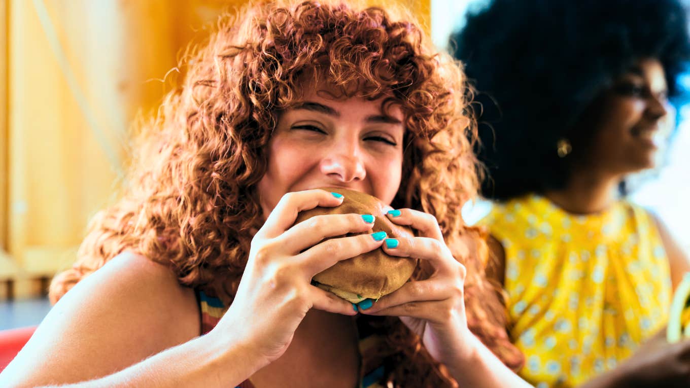 Woman eating a fast food burger that has been taken off the menu.