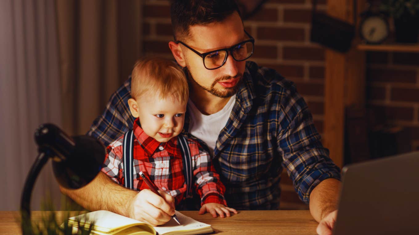 father working from home with son in lap 