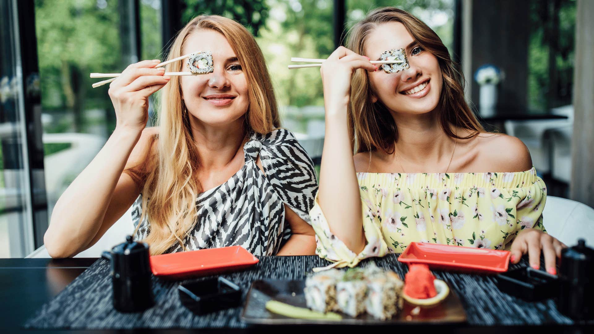 two women holding up sushi