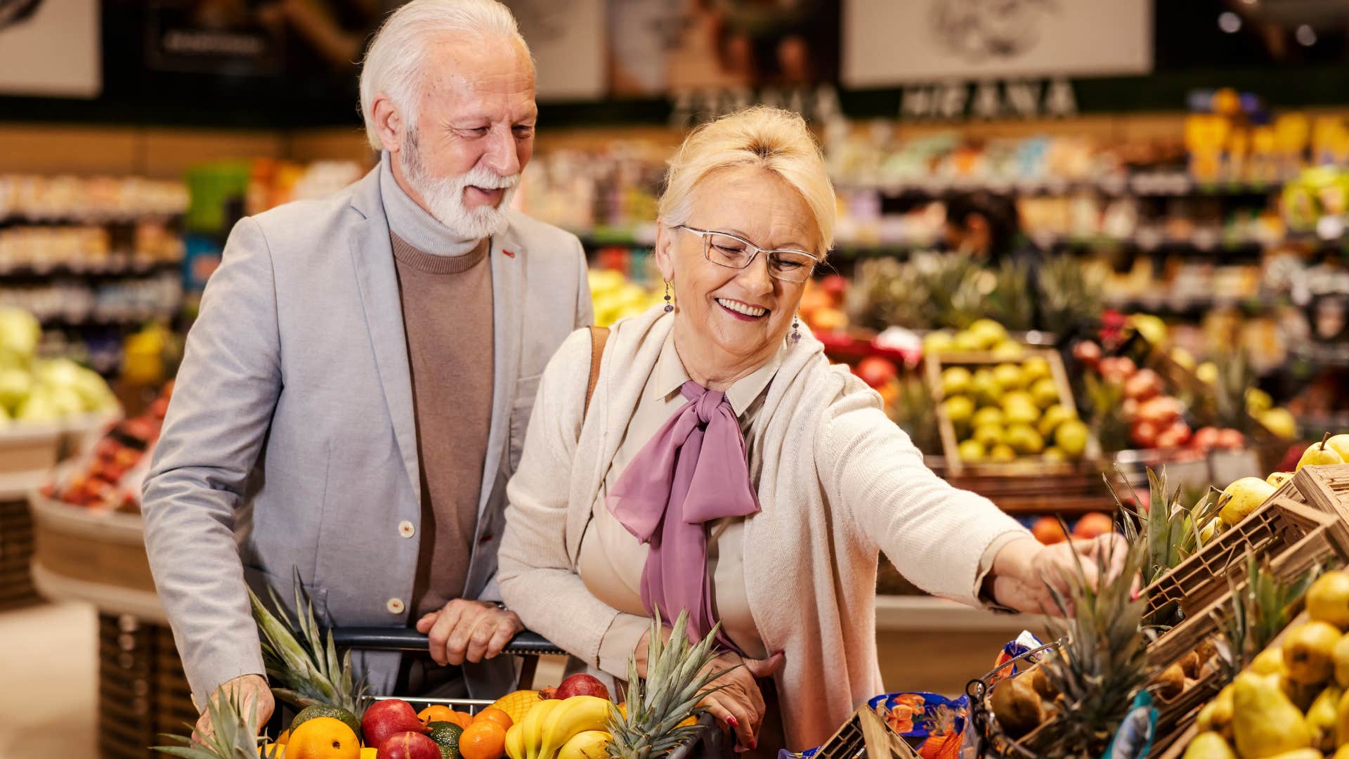 Older couple smiling and grocery shopping together